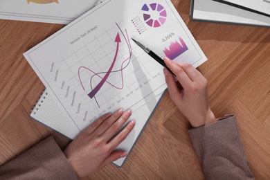 Photo of Businesswoman working with charts and graphs at table, top view. Investment analysis
