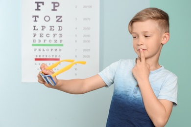 Photo of Cute little boy with eyeglasses in ophthalmologist office