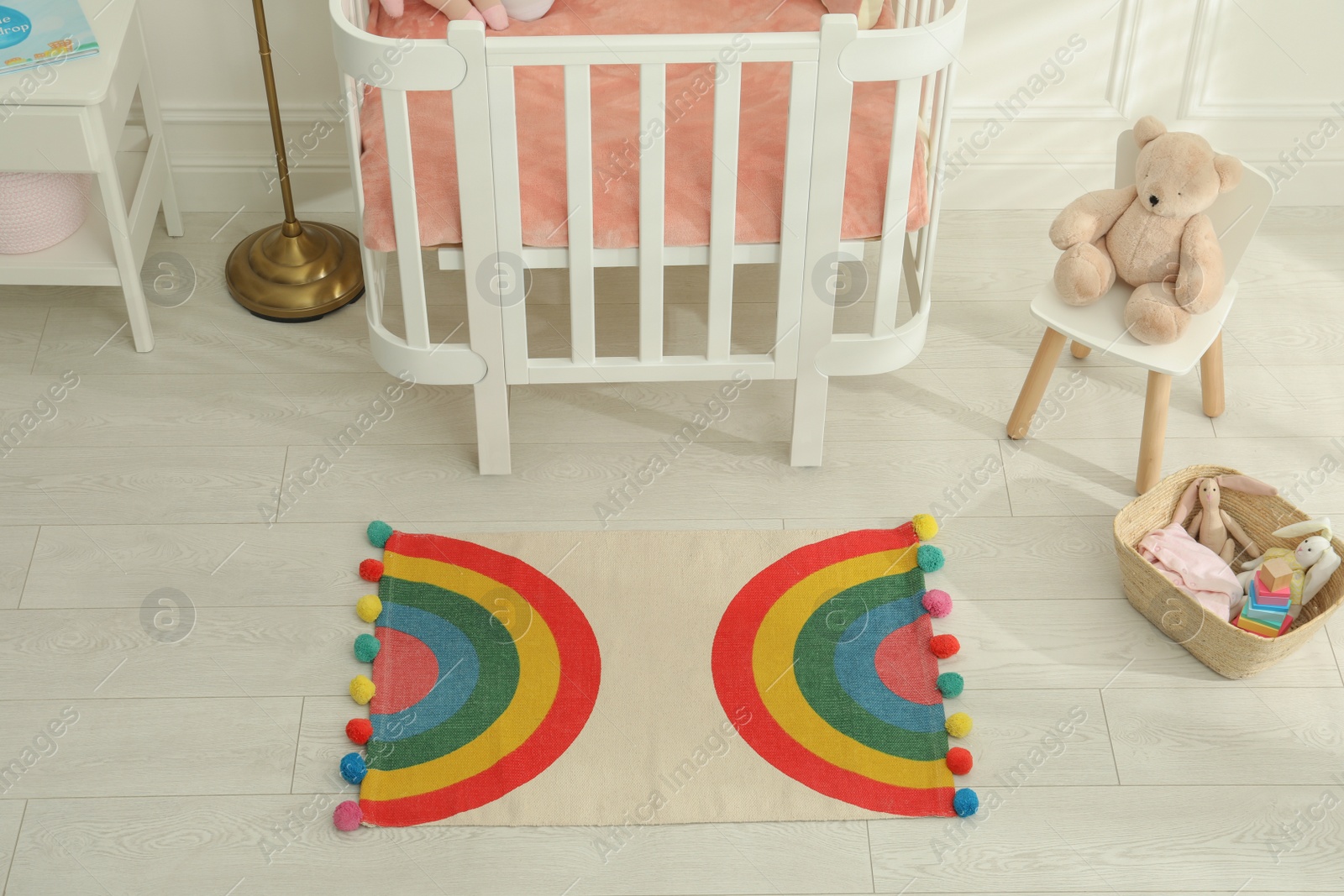 Photo of Stylish rug with rainbow on floor in baby room