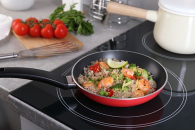 Photo of Tasty rice with shrimps and vegetables in frying pan on induction stove