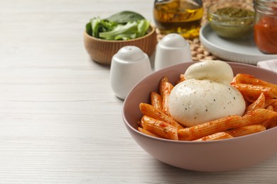 Photo of Bowl of delicious pasta with burrata and tomato sauce on white wooden table. Space for text