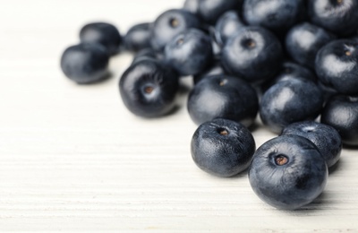 Photo of Fresh acai berries on white wooden table, closeup view. Space for text