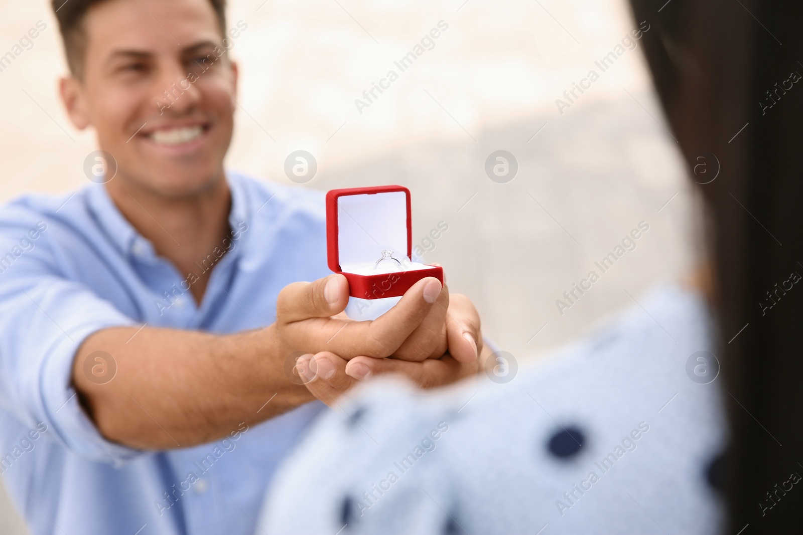 Photo of Man with engagement ring making proposal to his girlfriend outdoors, focus on hand