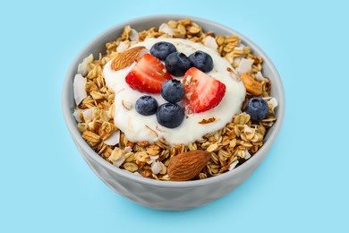 Photo of Tasty granola, yogurt and fresh berries in bowl on light blue background, closeup. Healthy breakfast