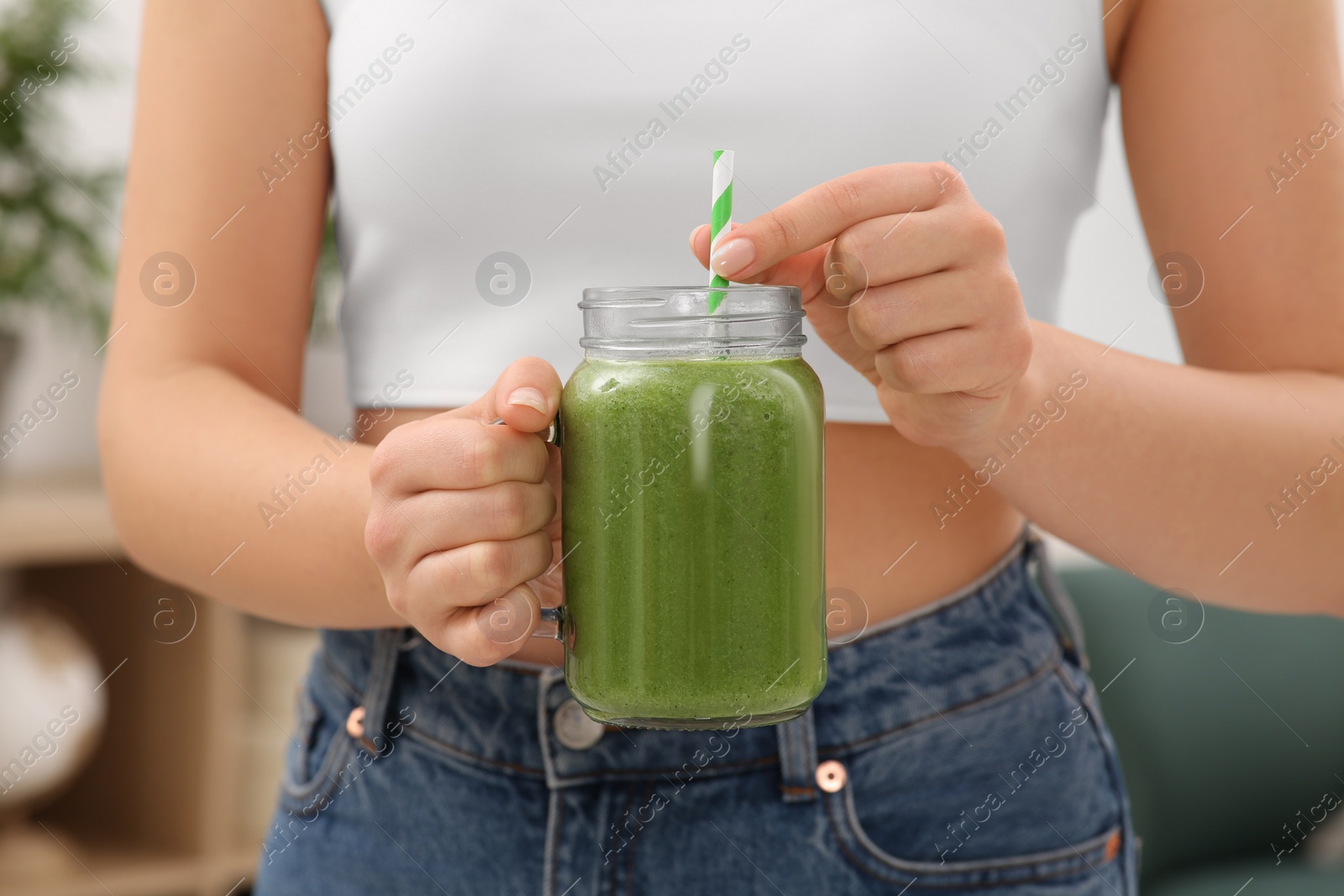 Photo of Woman holding mason jar with delicious smoothie indoors, closeup