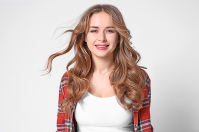 Portrait of young woman with long beautiful hair on light background