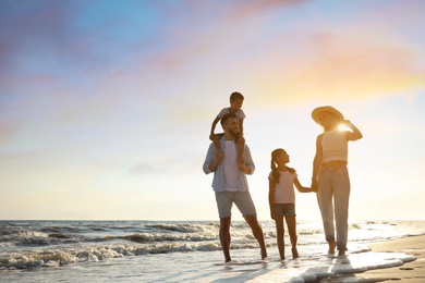 Photo of Happy family walking on sandy beach near sea