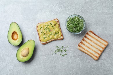 Photo of Delicious sandwich with guacamole and microgreens on grey table, flat lay