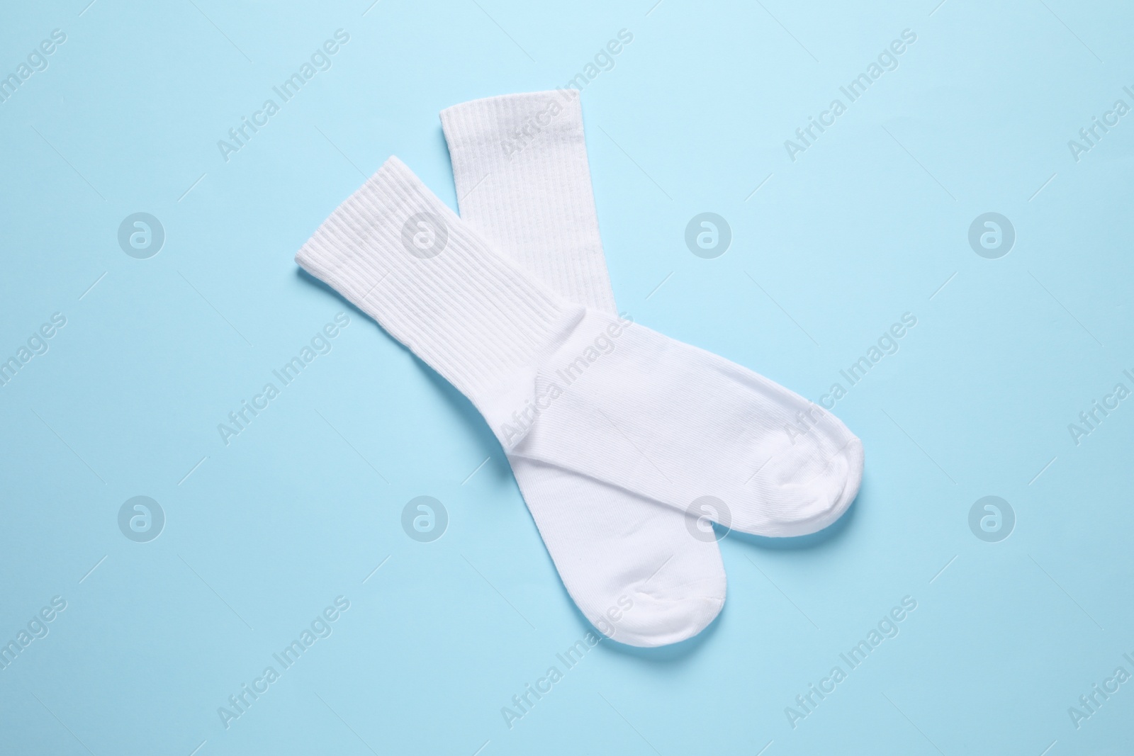 Photo of Pair of white socks on light blue background, flat lay
