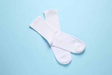 Pair of white socks on light blue background, flat lay