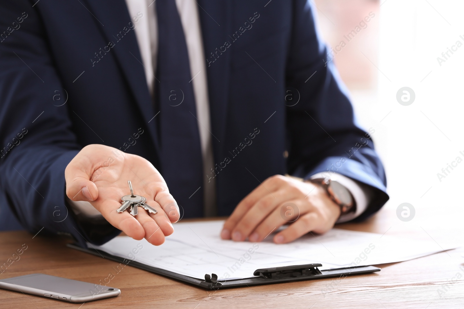 Photo of Real estate agent with keys at table in office, closeup