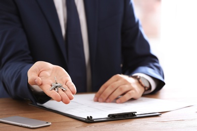Real estate agent with keys at table in office, closeup