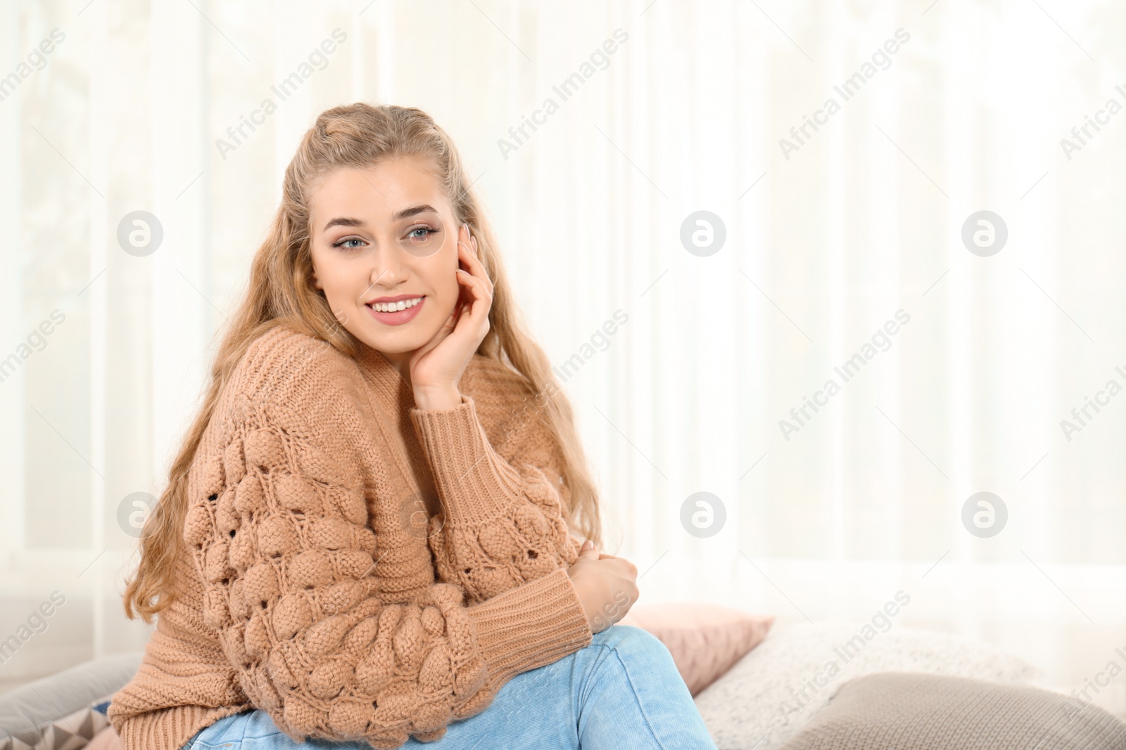 Photo of Attractive young woman in cozy warm sweater at home. Space for text