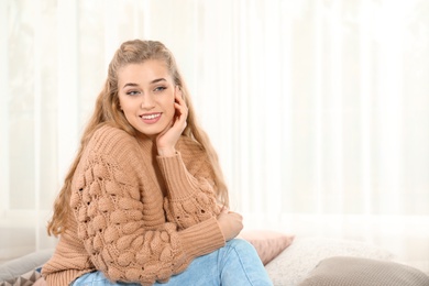 Photo of Attractive young woman in cozy warm sweater at home. Space for text