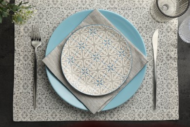 Photo of Stylish setting with cutlery, glasses and plates on black table, flat lay