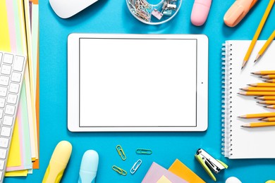 Modern tablet and stationery on light blue background, flat lay. Space for text