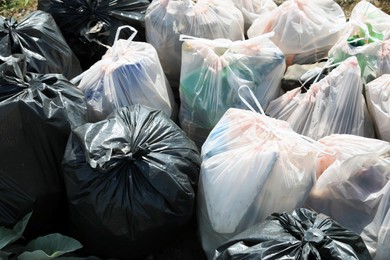 Photo of Many trash bags full of garbage outdoors, closeup. Environmental Pollution concept