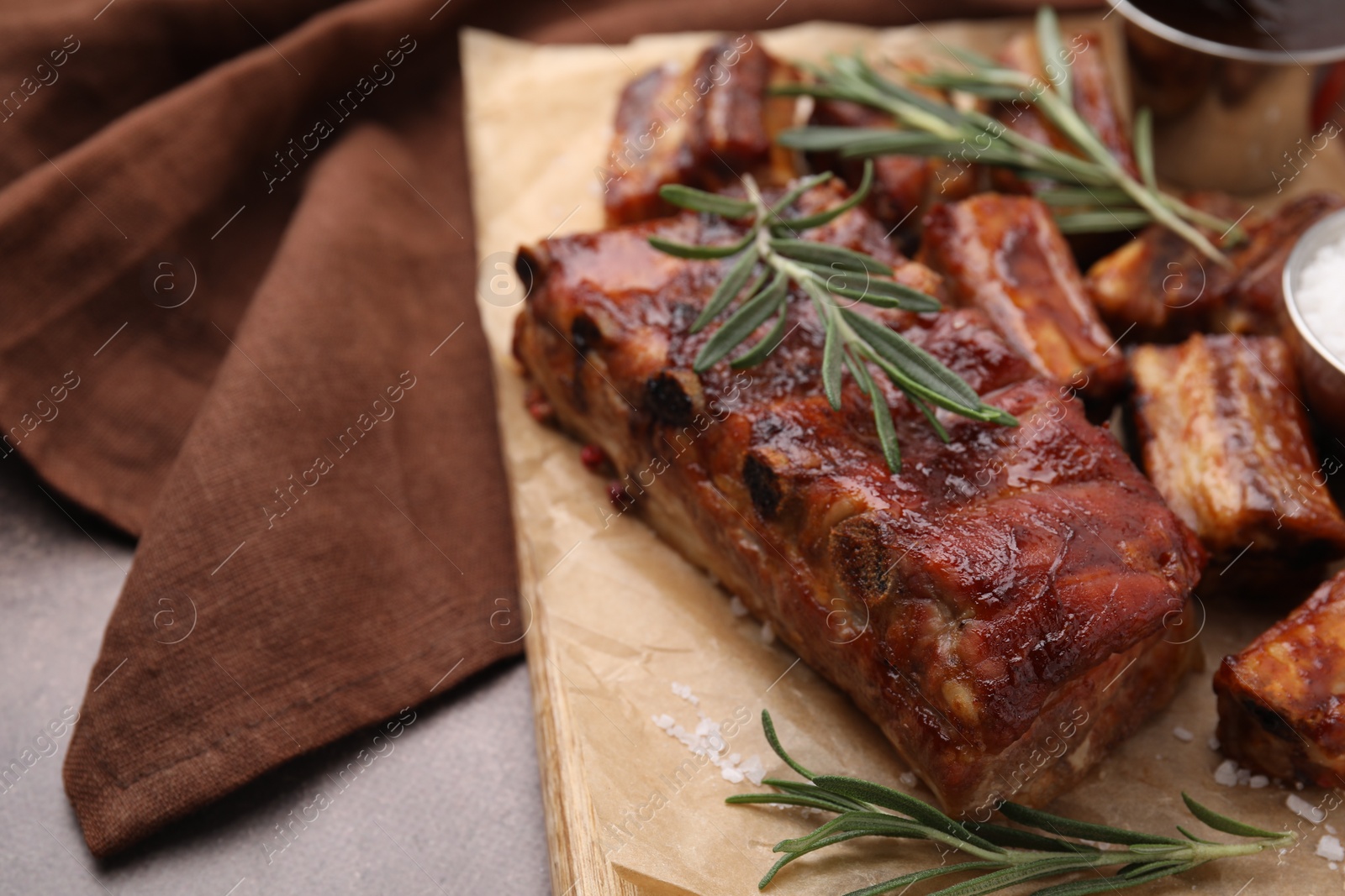 Photo of Tasty roasted pork ribs served with rosemary on brown table, closeup. Space for text