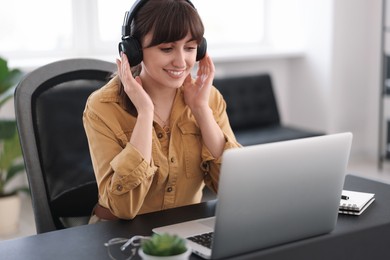 Woman in headphones watching webinar at table in office