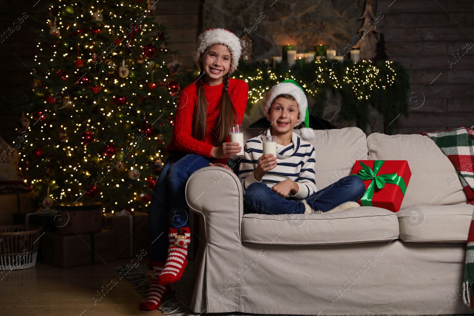 Photo of Happy children with glasses of milk at home. Christmas time