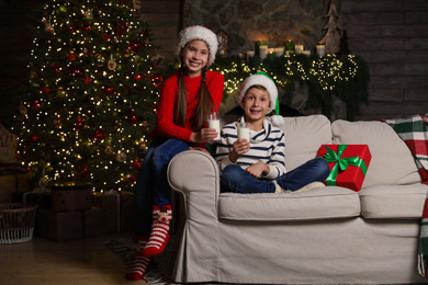 Photo of Happy children with glasses of milk at home. Christmas time