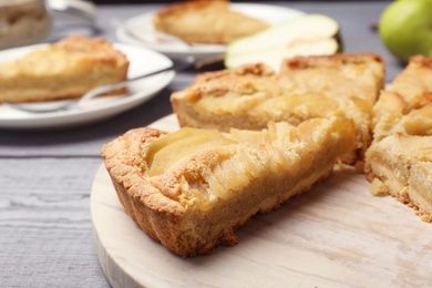 Photo of Cut delicious sweet pear tart on wooden table, closeup