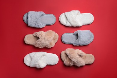 Photo of Different soft fluffy slippers on red background, flat lay