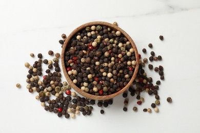 Aromatic spice. Different peppers in bowl on white marble table, top view