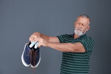 Photo of Man putting capsule shoe freshener in footwear on color background