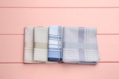 Photo of Different handkerchiefs folded on pink wooden table, flat lay