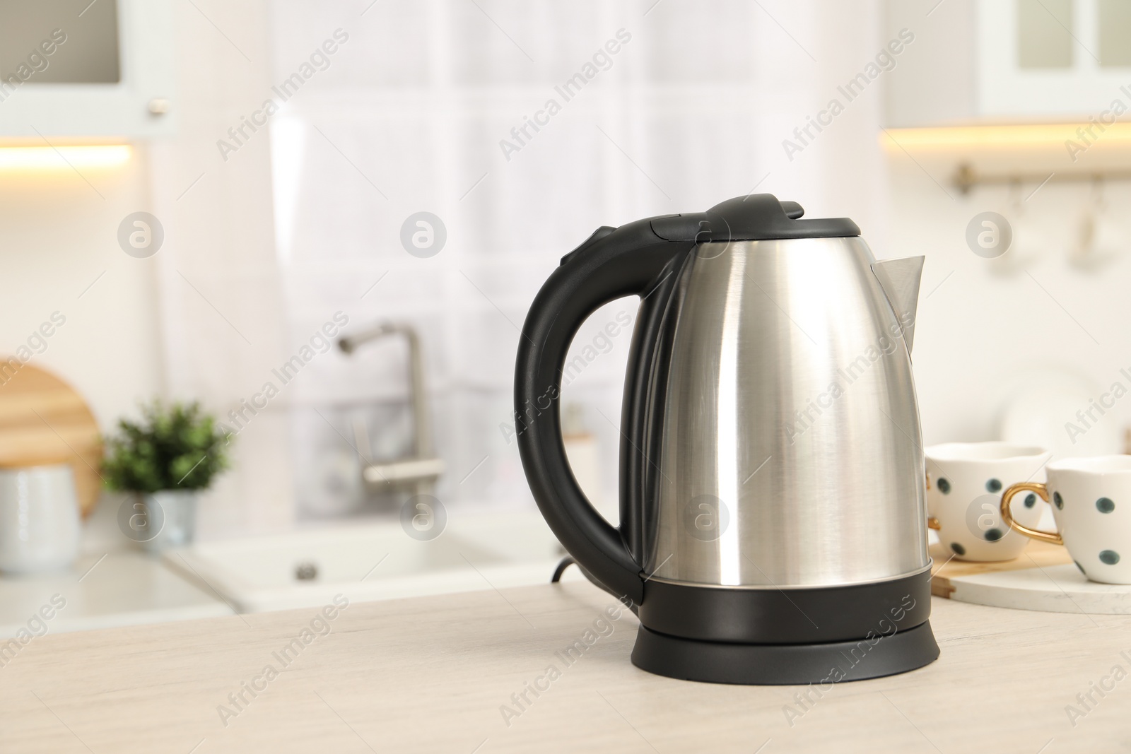 Photo of Modern electric kettle on table in kitchen. Space for text