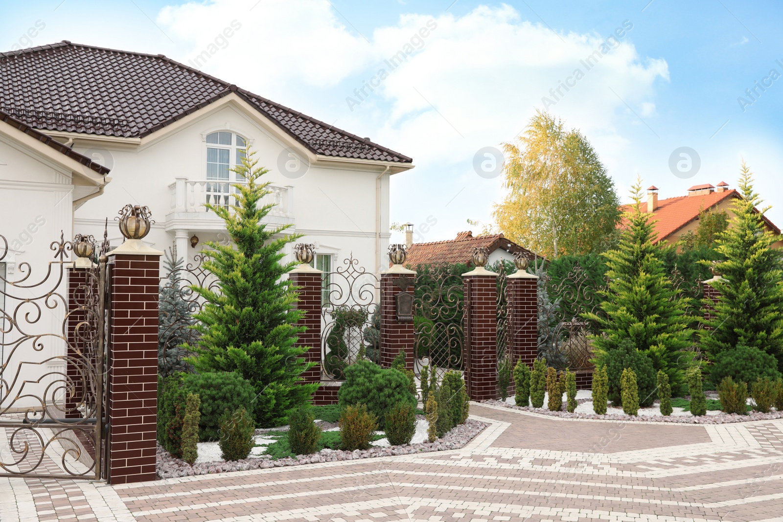 Photo of Beautiful cottage exterior with elegant fence and many green plants