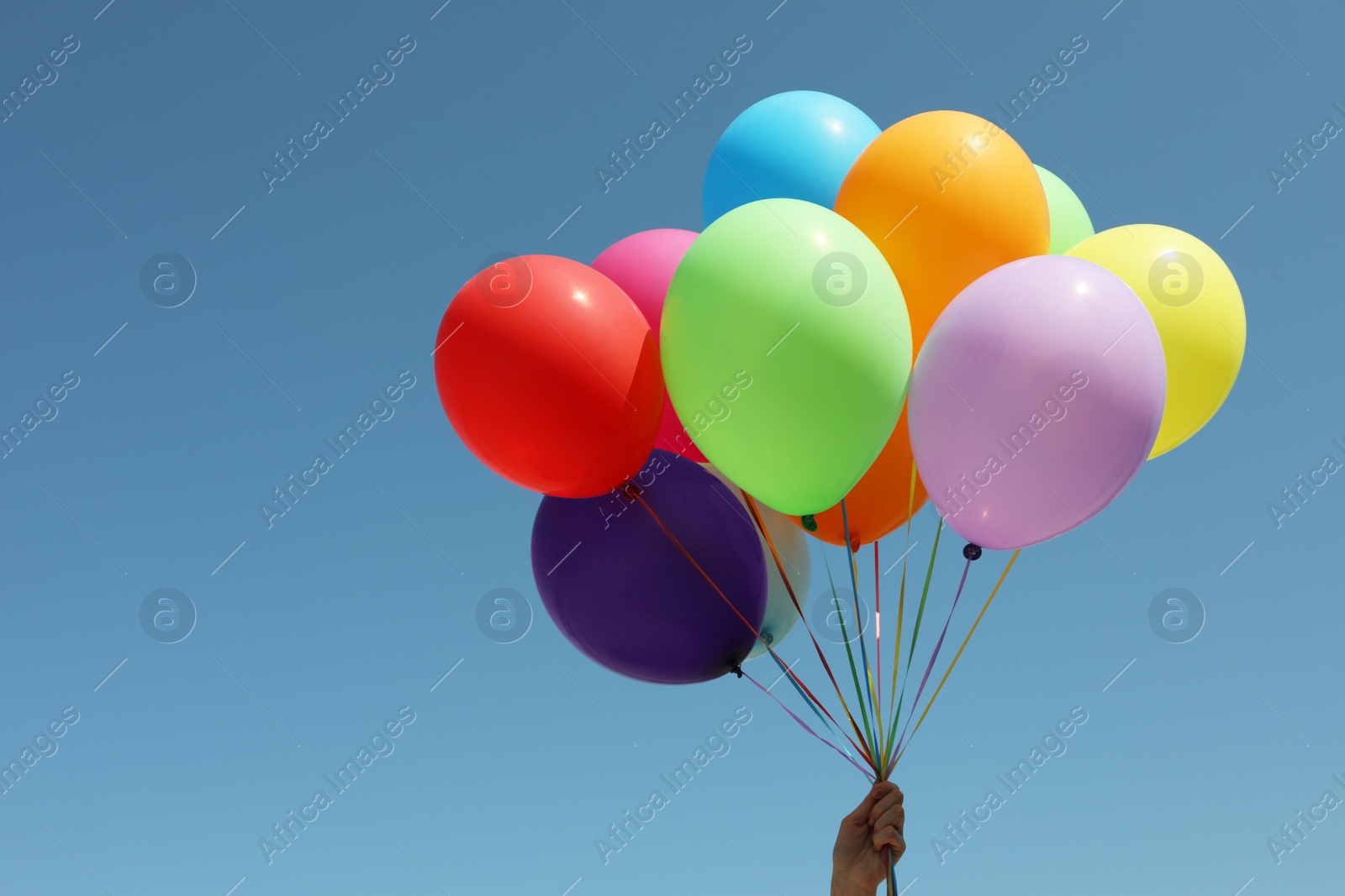 Photo of Woman with bunch of colorful balloons against blue sky, closeup. Space for text