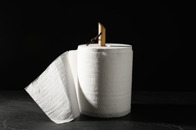 Photo of Holder with roll of white paper towels on grey table against black background