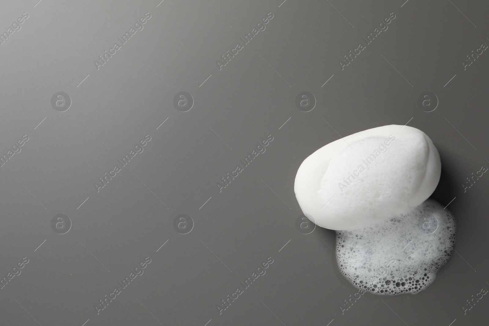 Photo of Soap with fluffy foam on grey background, top view. Space for text