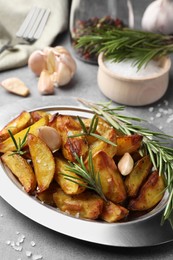 Tasty baked potato and aromatic rosemary served on grey textured table