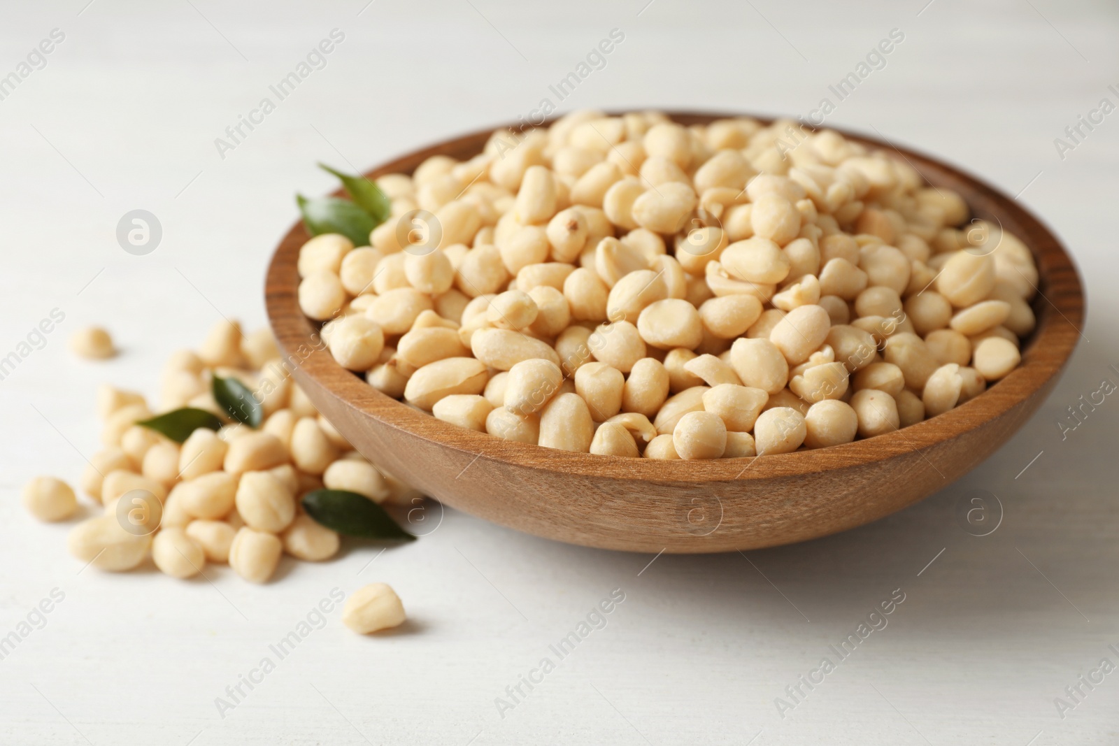 Photo of Shelled peanuts in wooden bowl on table