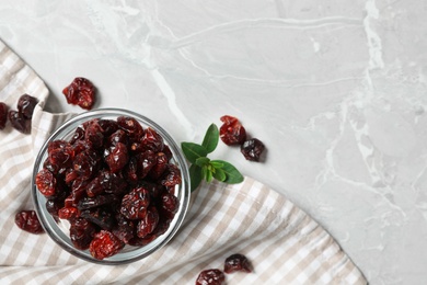 Photo of Bowl of dried cranberries on light grey marble table, flat lay. Space for text