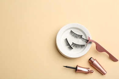 Flat lay composition with magnetic eyelashes and accessories on beige background. Space for text