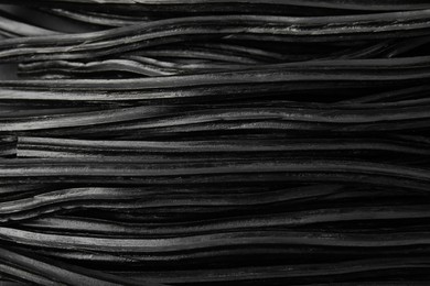 Tasty black liquorice candies as background, top view