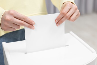 Photo of Woman putting her vote into ballot box on blurred background, closeup