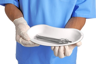 Photo of Male doctor holding dish with medical tools on white background, closeup. Medical objects