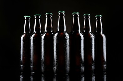 Many bottles of beer on table against dark background