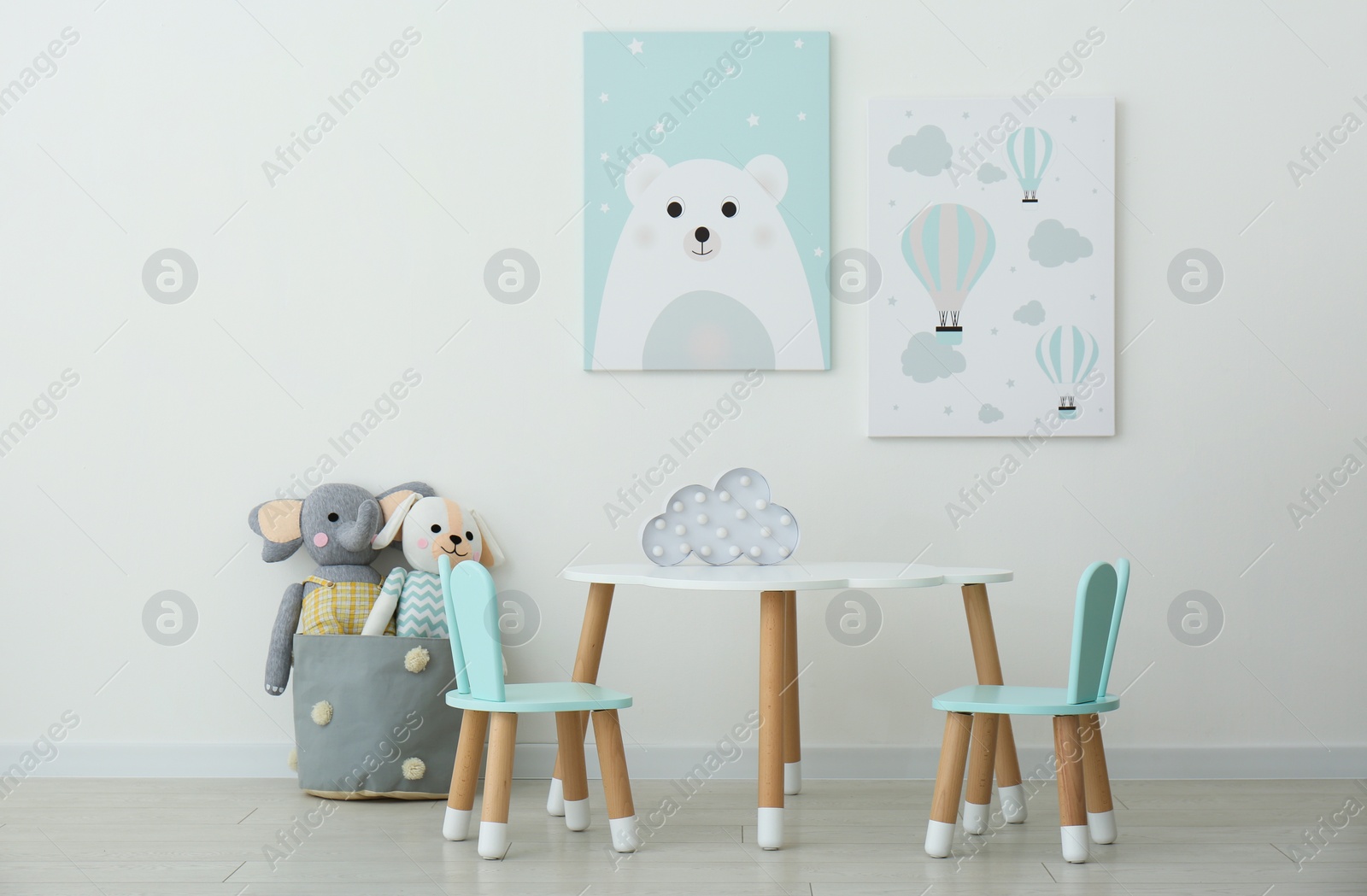 Photo of Adorable wall art, table and chairs with bunny ears in children's room interior