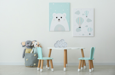 Adorable wall art, table and chairs with bunny ears in children's room interior