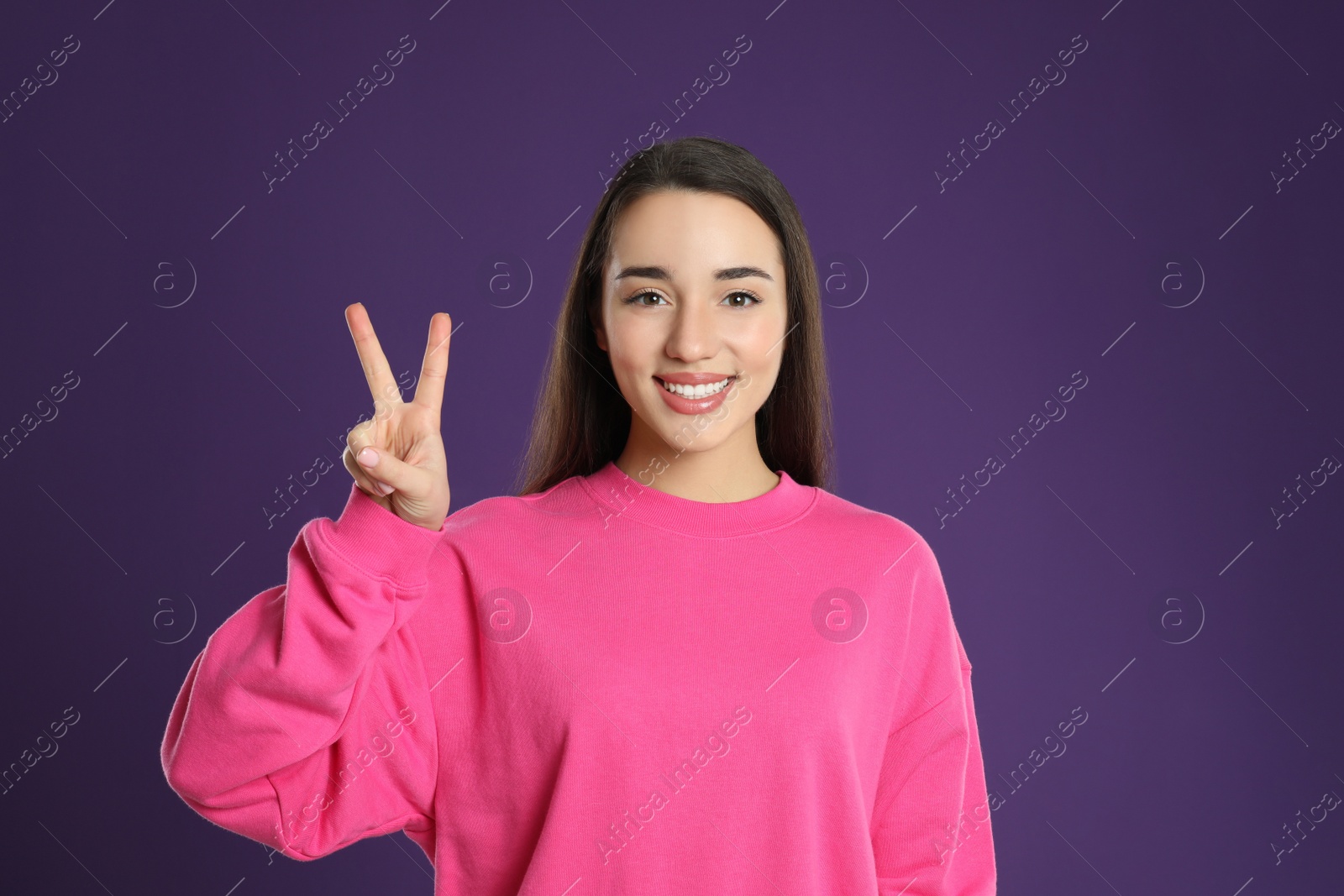 Photo of Woman showing number two with her hand on purple background