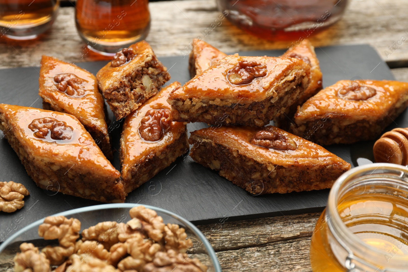 Photo of Delicious sweet baklava with walnuts and honey on wooden table