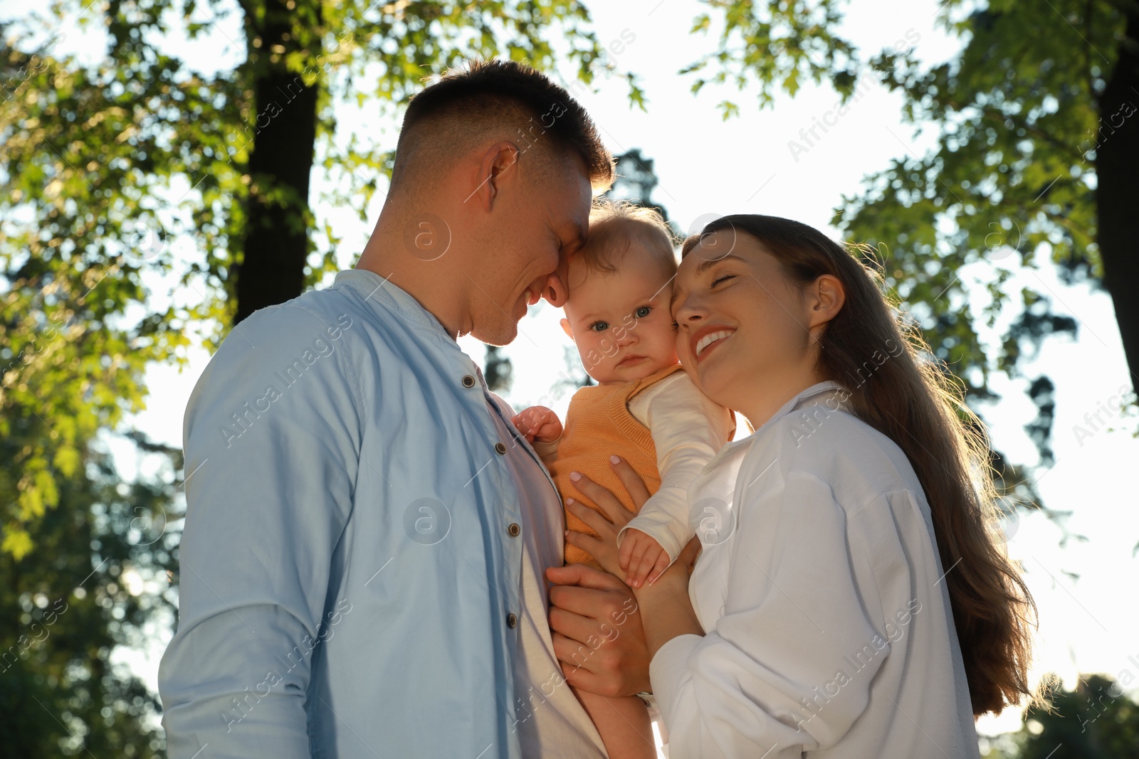 Photo of Parents with their cute daughter spending time together in park on summer day