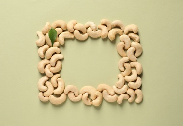 Frame made with tasty cashew nuts on color background, top view. Space for text