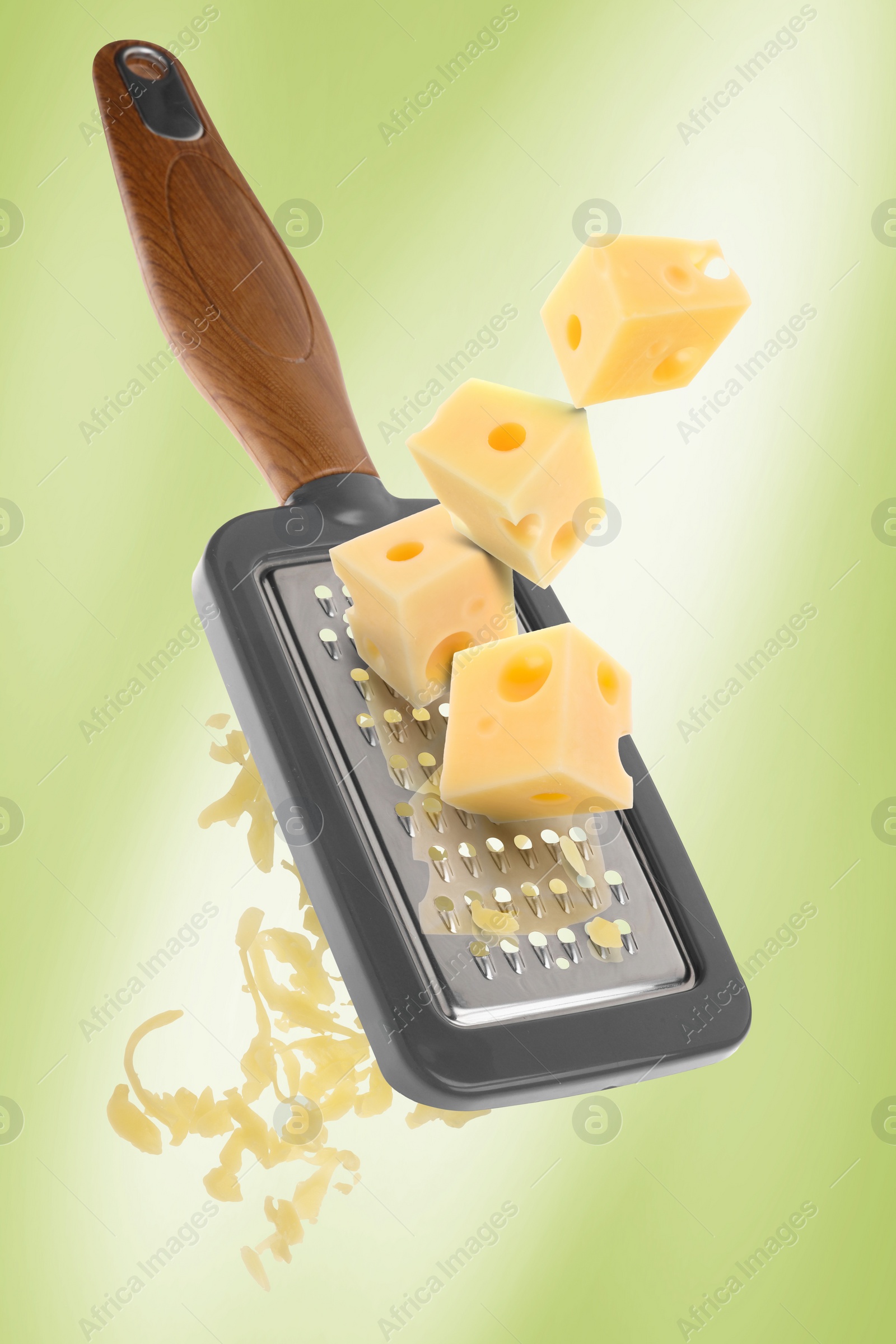 Image of Grating cheese with hand grater on yellowish green background